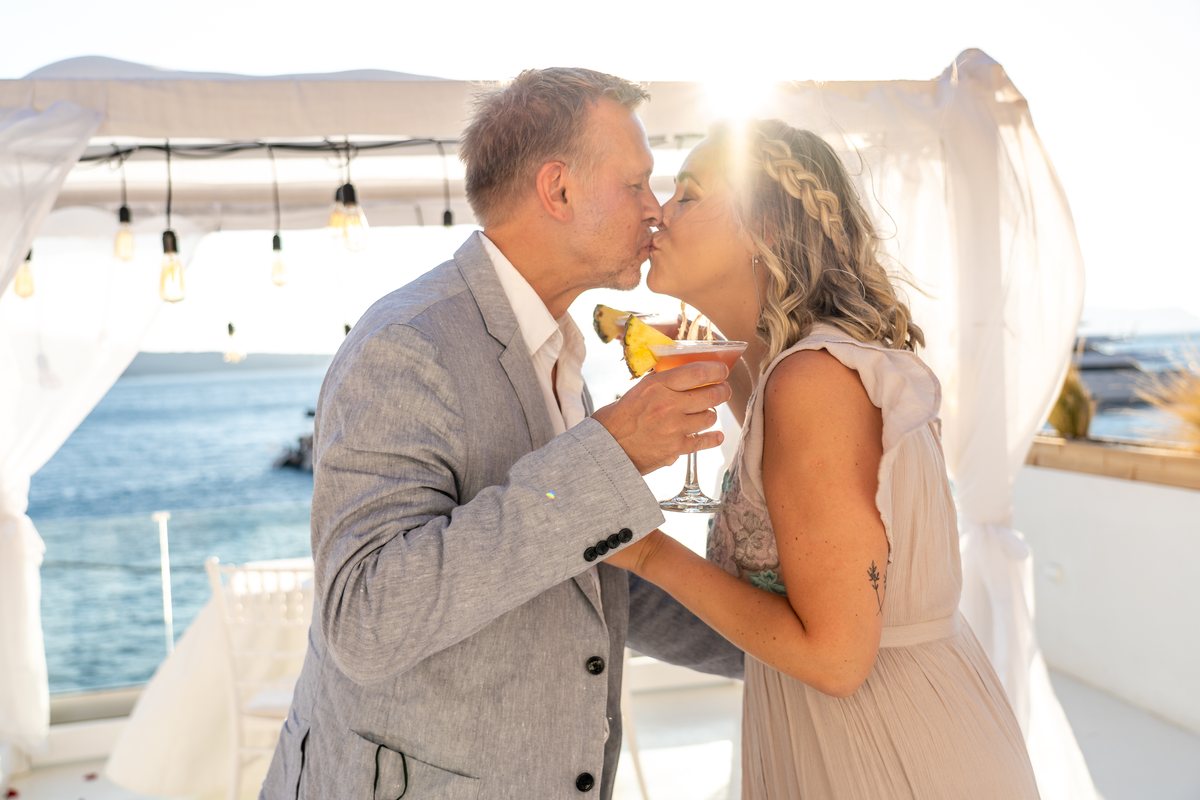 A couple with cocktails at their table on AION's terrace as the sun goes down