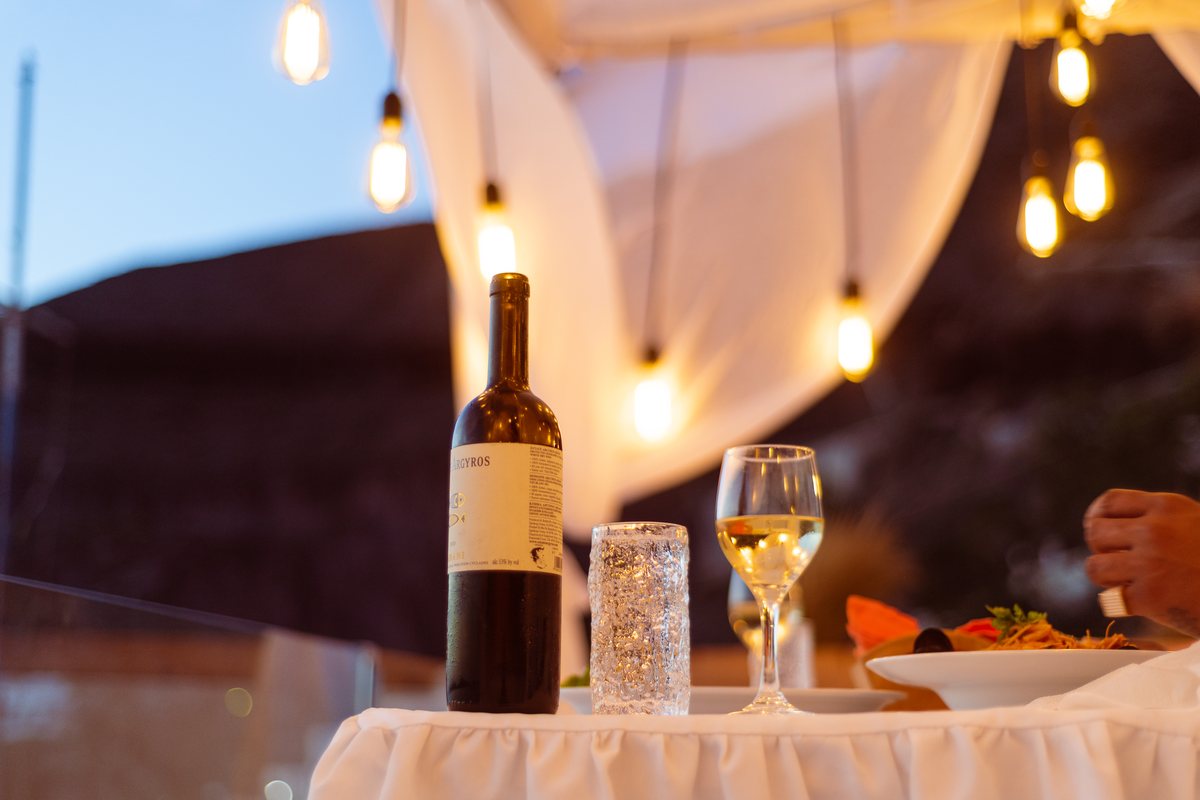 Wine poured at a private dinner on AION's terrace, bulbs lit overhead