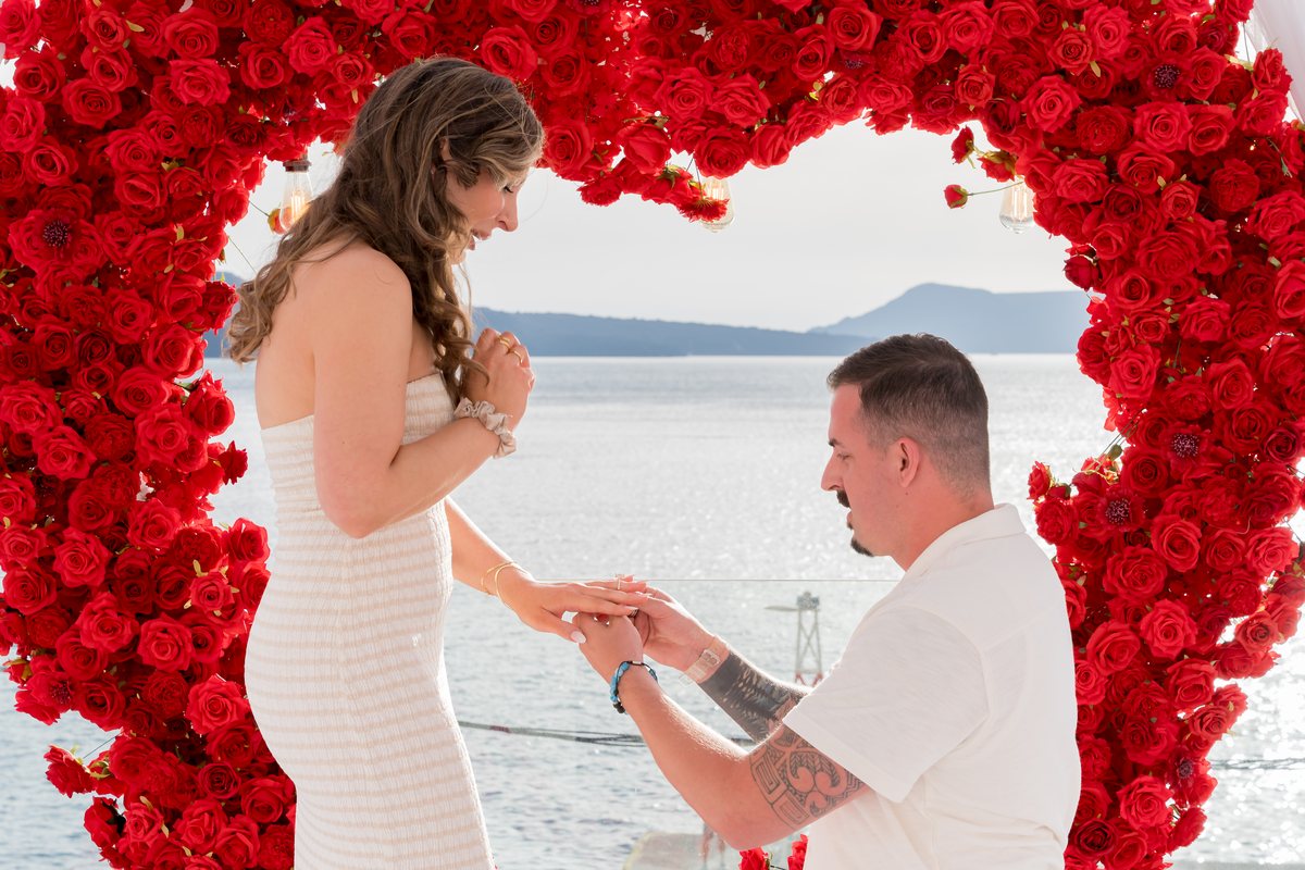 A proposal on one knee framed inside the red rose heart on AION's terrace