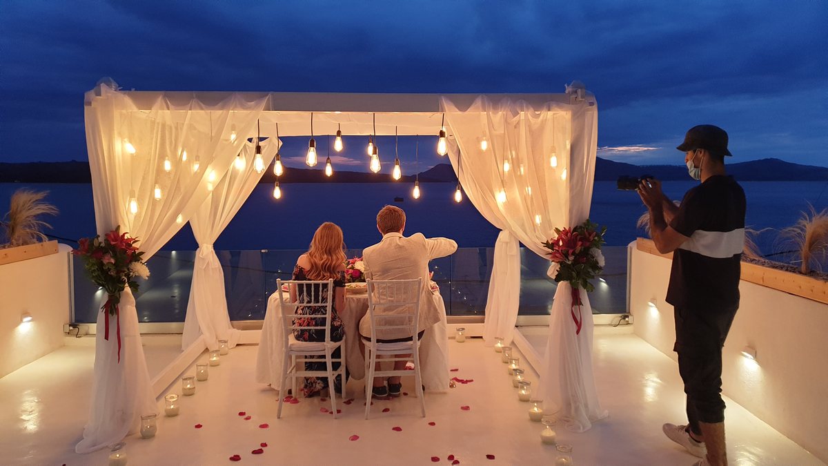 An evening on AION's terrace — the table laid, candles down the floor and the caldera beyond