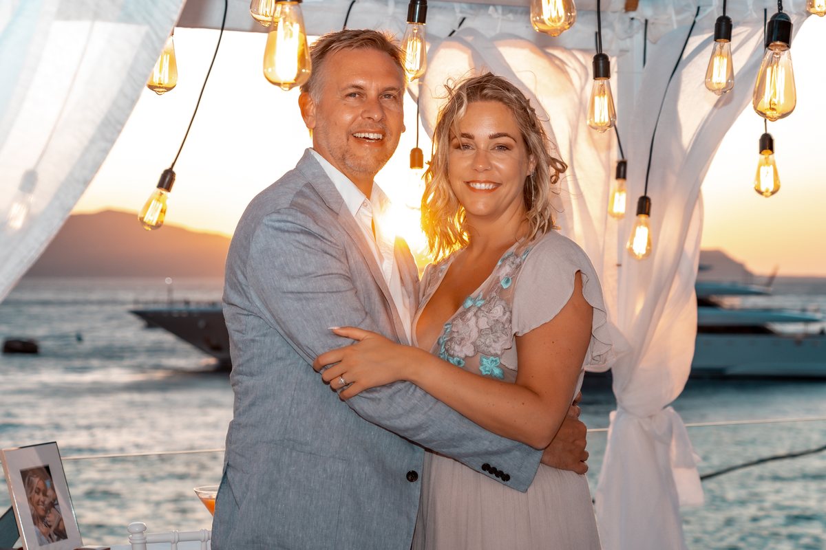 A couple photographed on AION's terrace as the sun drops behind the caldera