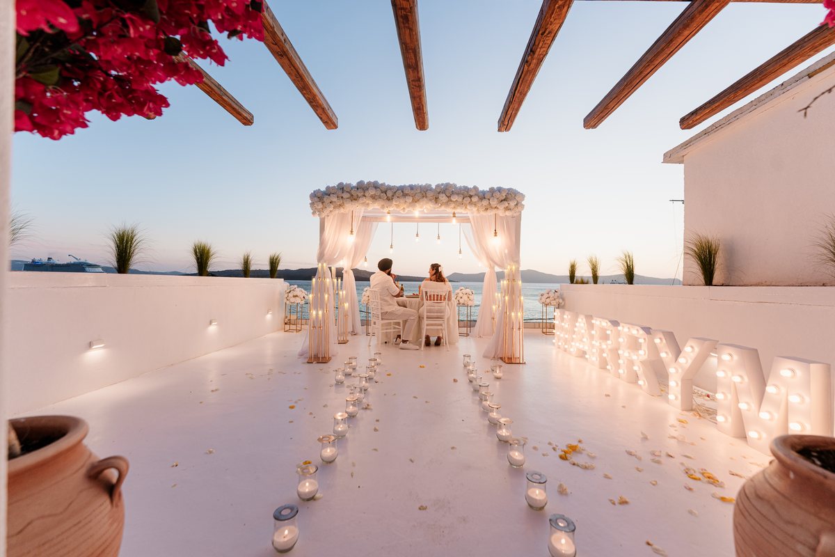 AION's terrace at dusk — the arch lit, a candle aisle and MARRY ME on the far wall