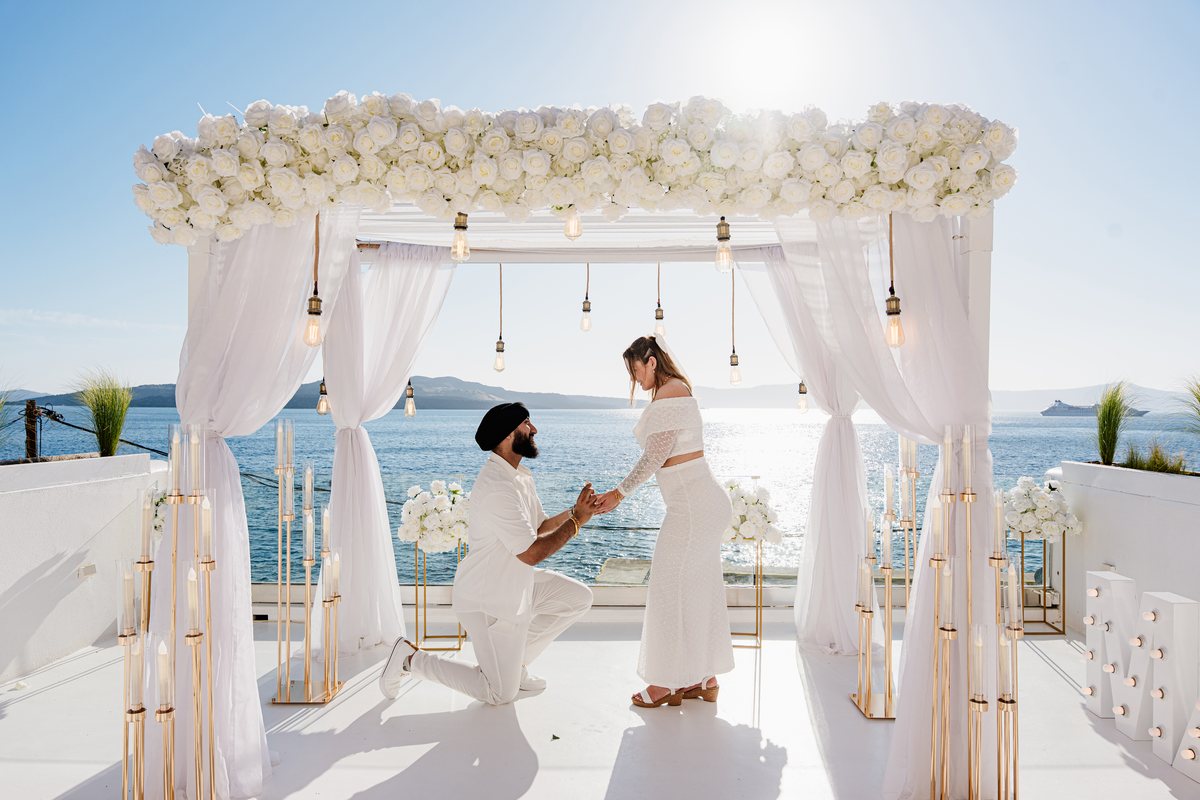 A ceremony on AION's terrace — the white flower arch, gold stands and the Aegean straight ahead