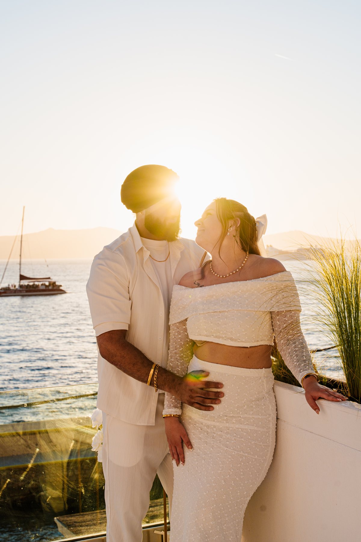 A married couple on AION's terrace as the sun goes down behind the caldera