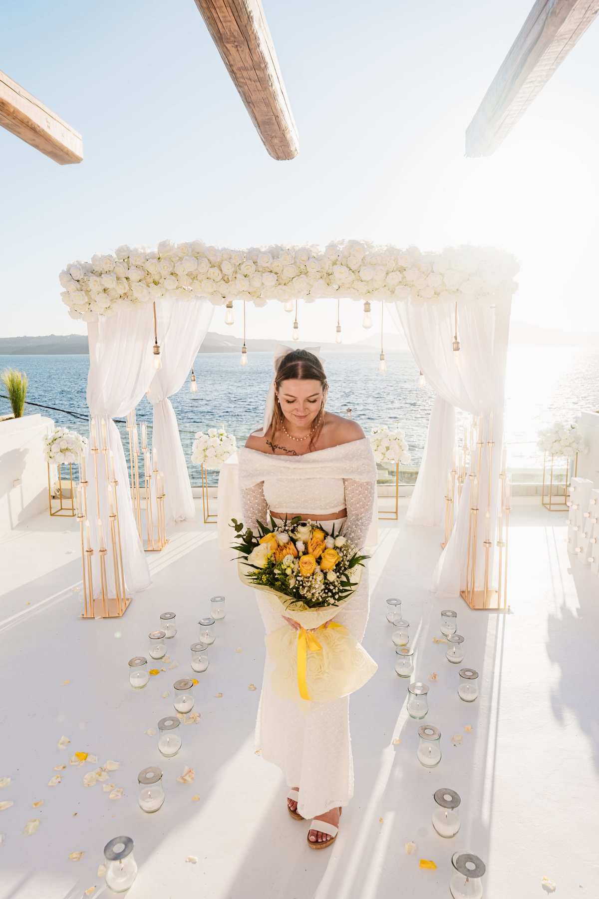 Vows exchanged under the white flower arch on AION's private terrace in Fira