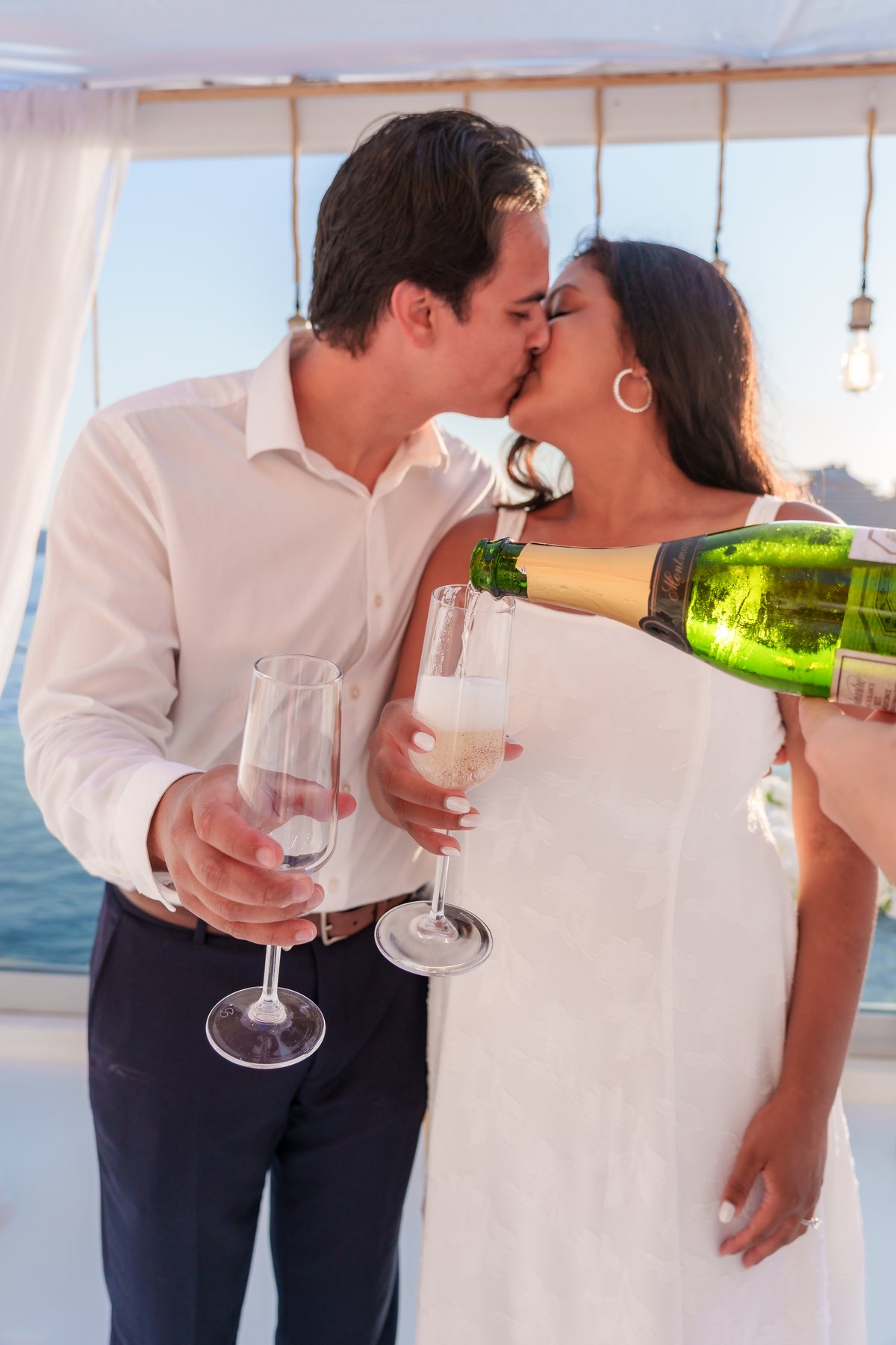 Champagne poured under AION's white flower canopy, a newly engaged couple kissing