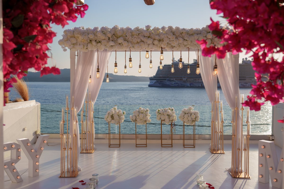 AION's white flower canopy at sunset, seen under the bougainvillea with the caldera behind