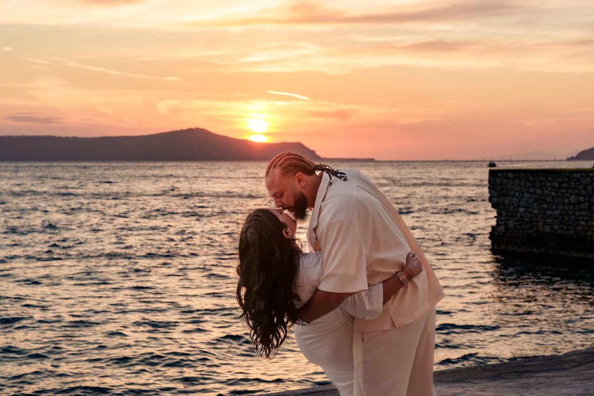 Sunset at Ormos Firon — a couple at the water's edge on the old port breakwater at AION