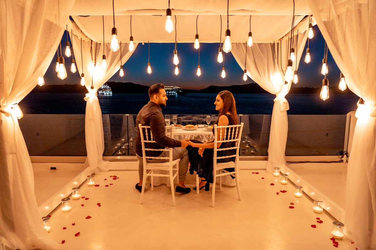 A couple at their candlelit table under AION's lit canopy at blue hour