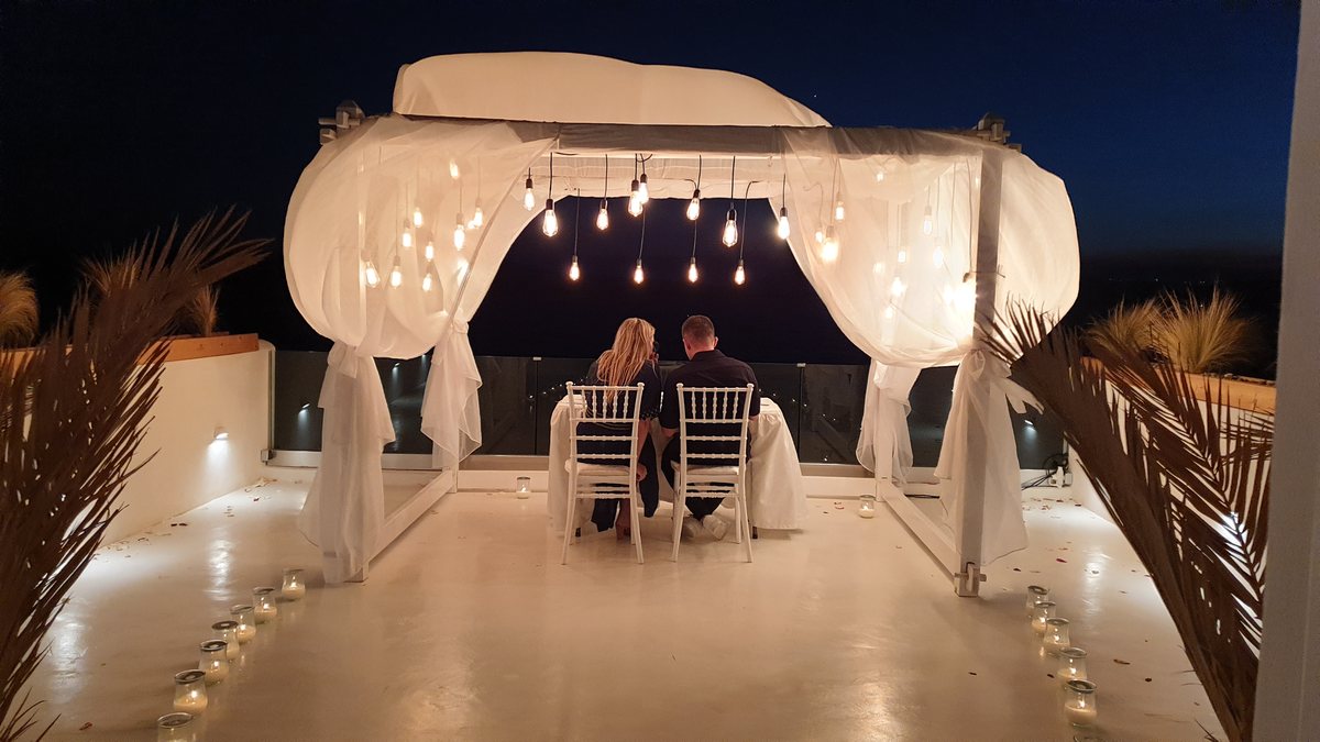 A candlelit table for two set for a proposal dinner on AION's terrace