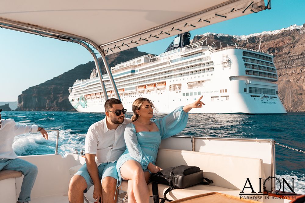 Crossing the caldera by boat, the cliffs of Fira and a liner behind