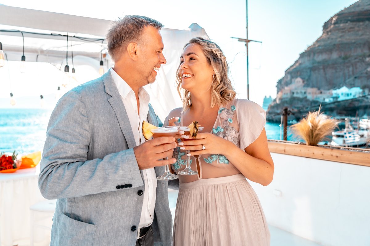 Scot and his fiancee-to-be with cocktails on AION's terrace, the sun low behind them