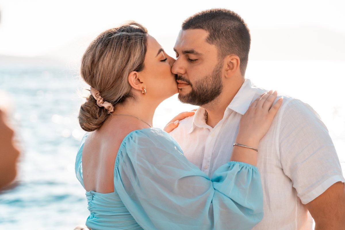 A newly engaged couple kissing on the caldera side of Fira