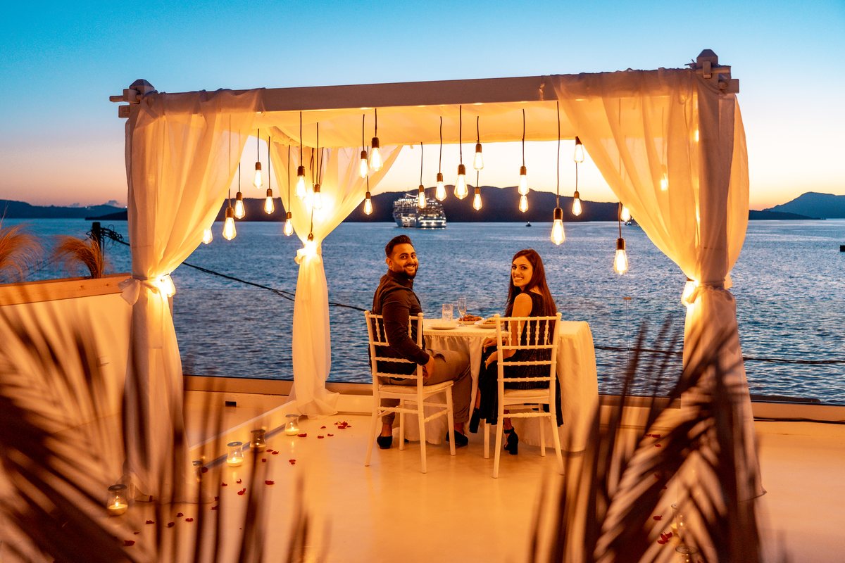 Dinner for two on AION's terrace at golden hour, the whole caldera to themselves